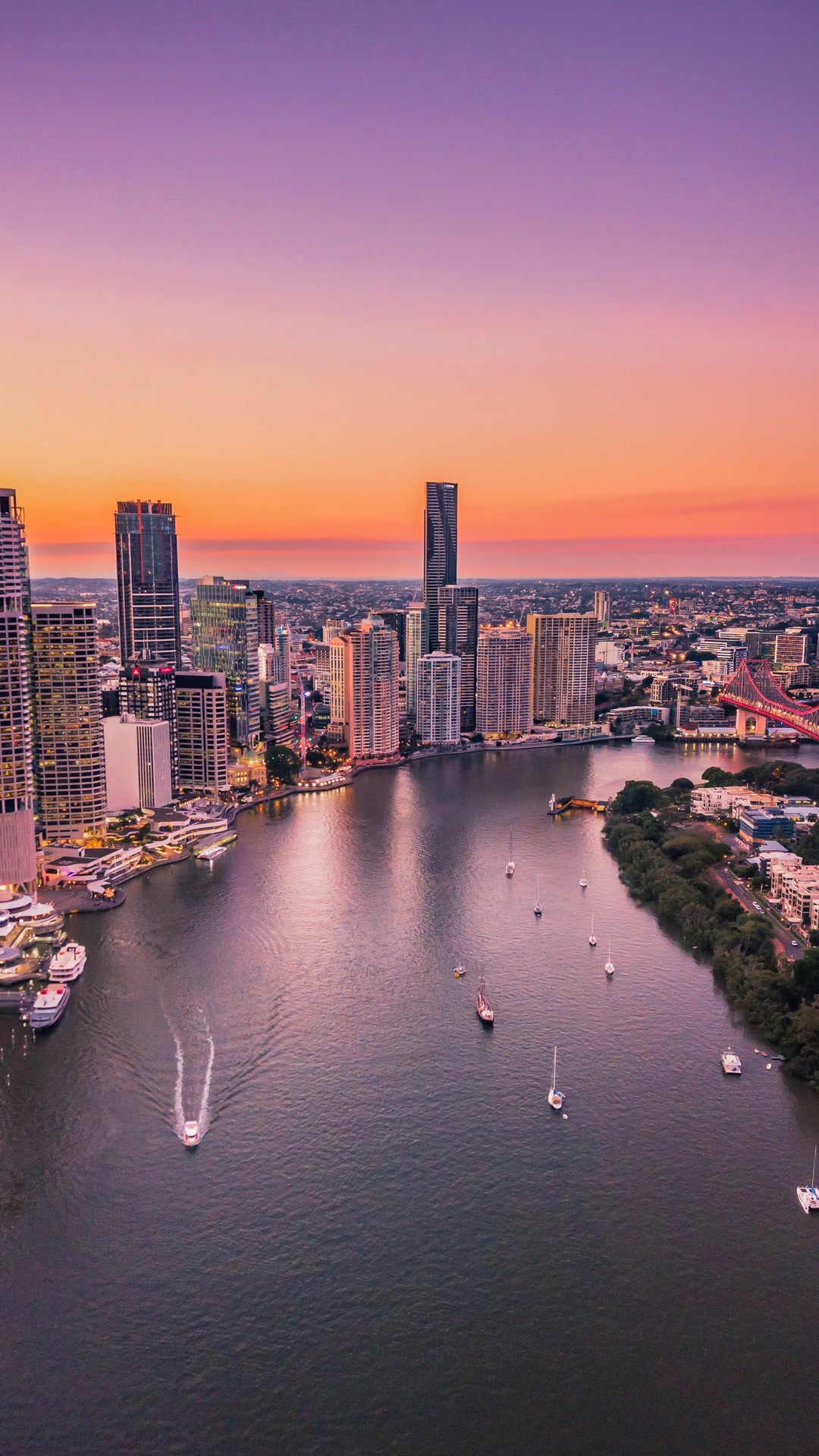 Aerial view of the Brisbane River and city skyline at sunset.