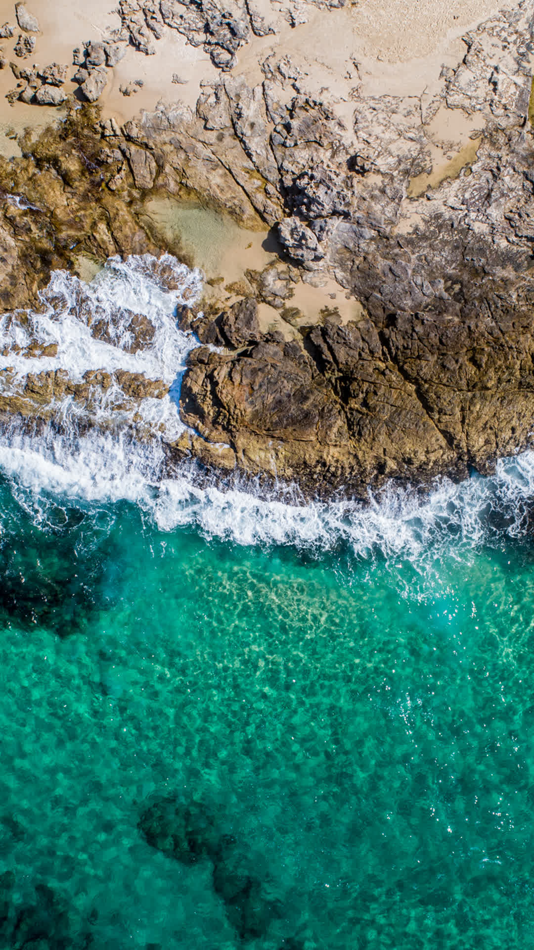 Aerial view of rocky island coastline and clear water.