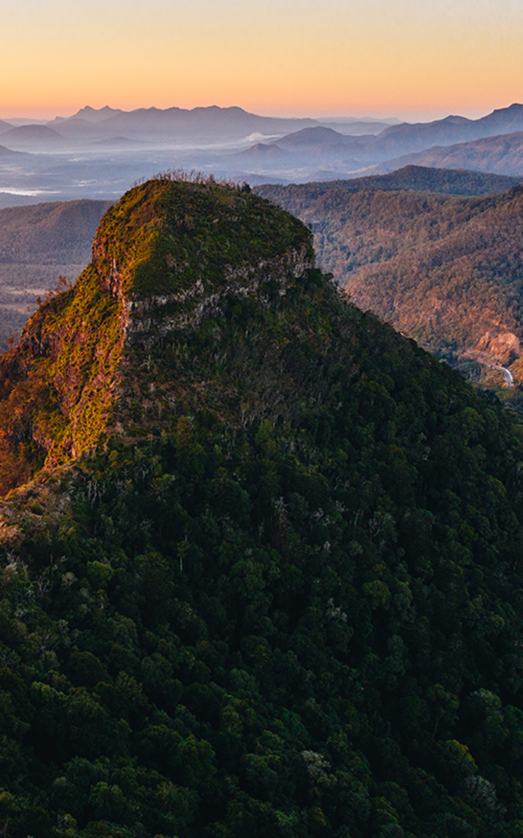 Sunrise light across a prominent Scenic Rim mountain and surrounding ranges.