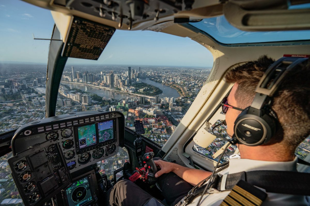 Pilot flying over Brisbane city in a helicopter cockpit