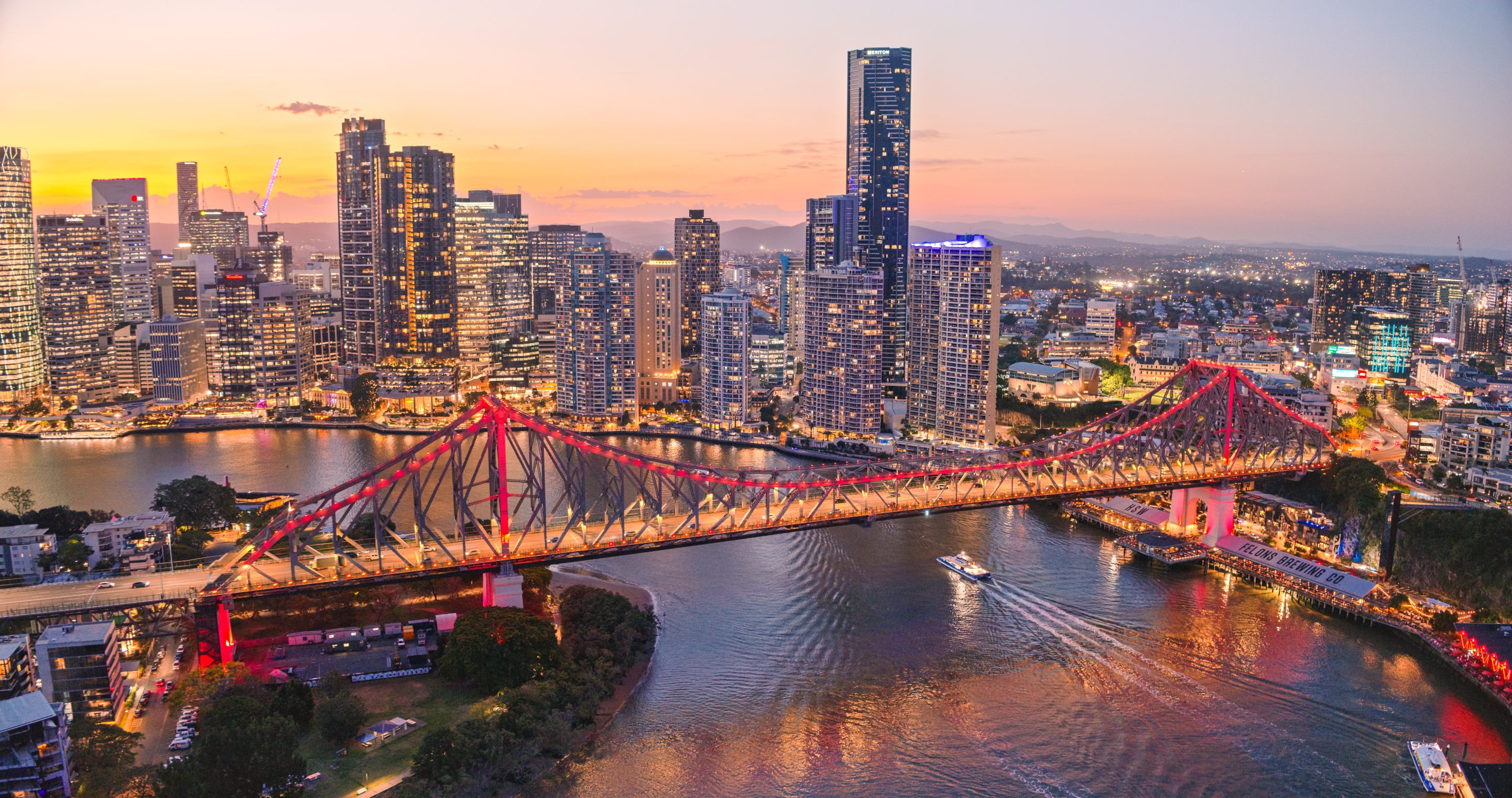 Aerial view of Brisbane River and Story Bridge at sunset.