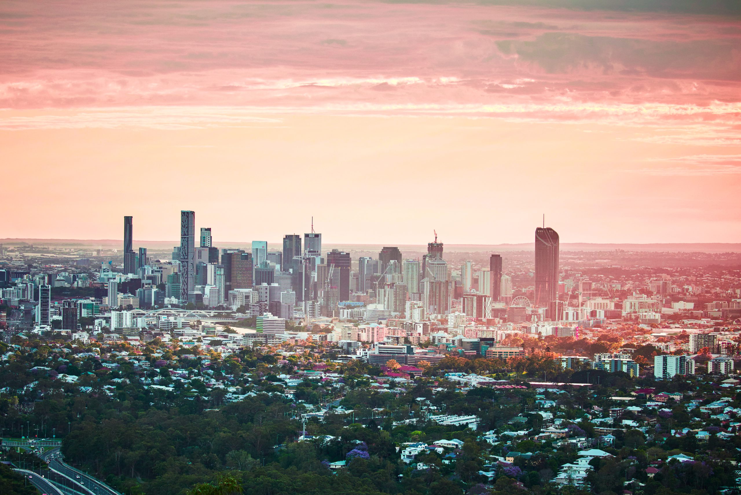 Brisbane city skyline under pink sunrise cloud