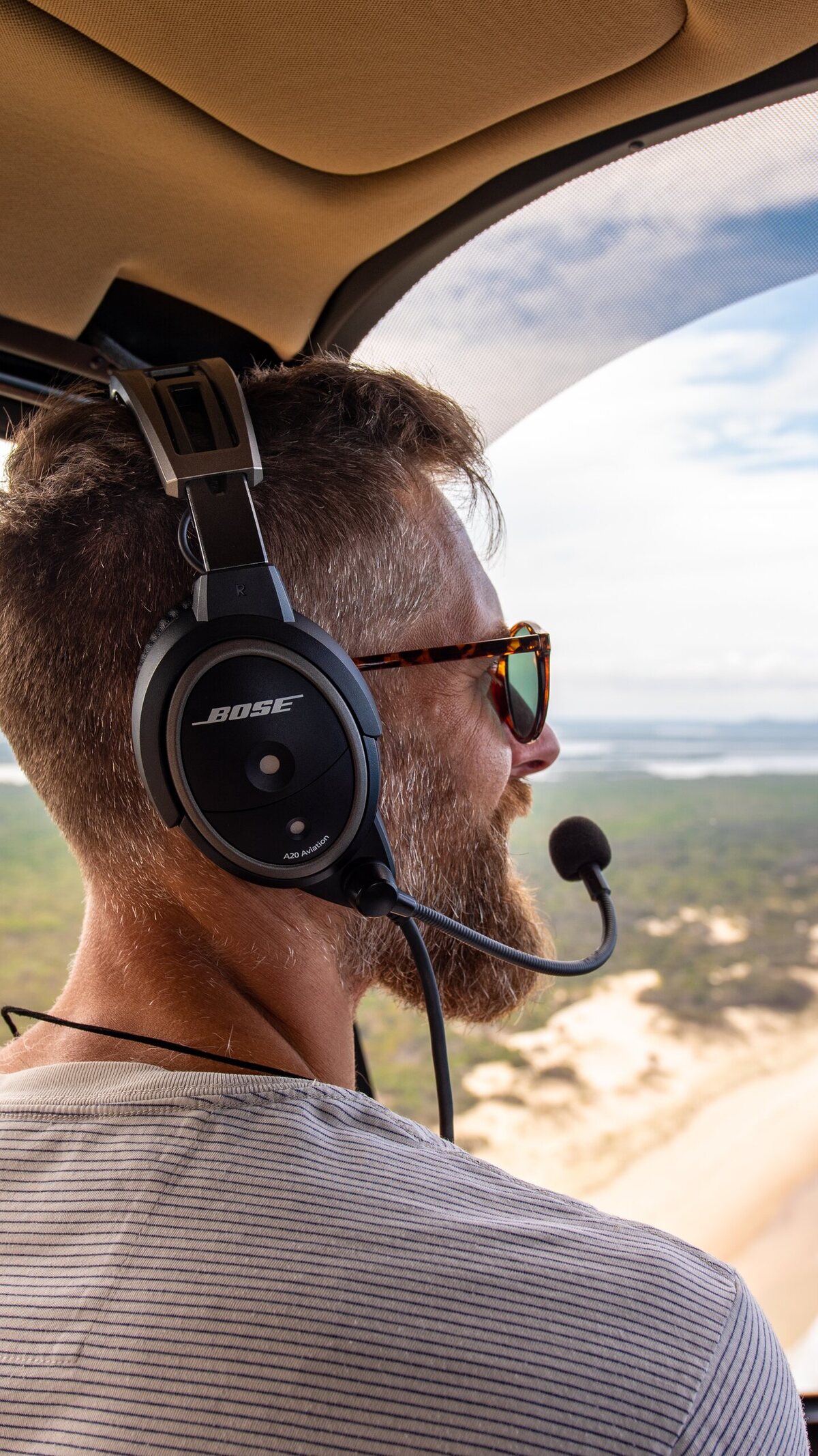 Passenger flying by helicopter above a forested island coastline.