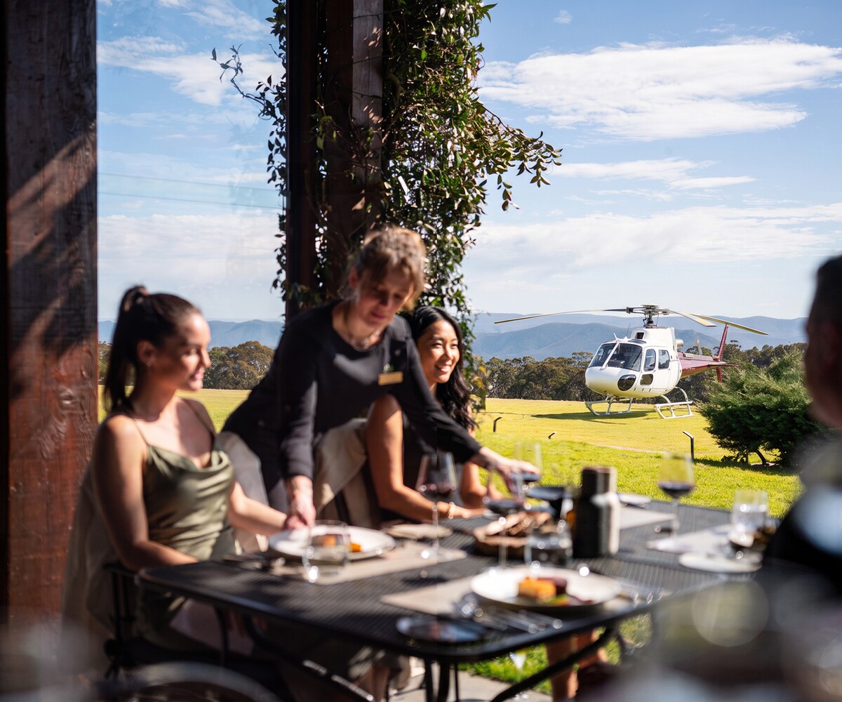 Guests dining at Spicers Peak Lodge with a helicopter on the lawn