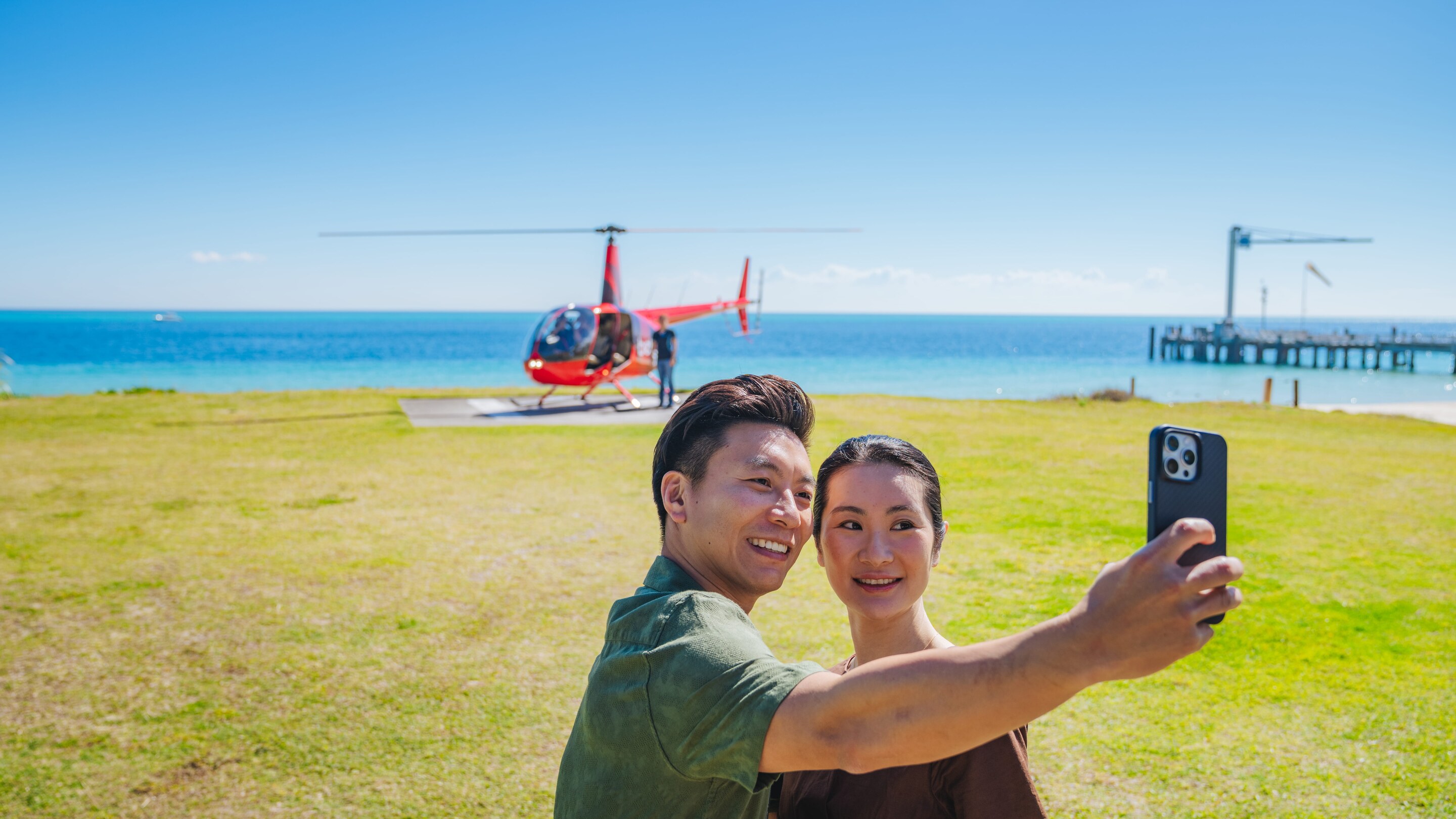 Couple taking a selfie with a Bekaa Air helicopter at Tangalooma.
