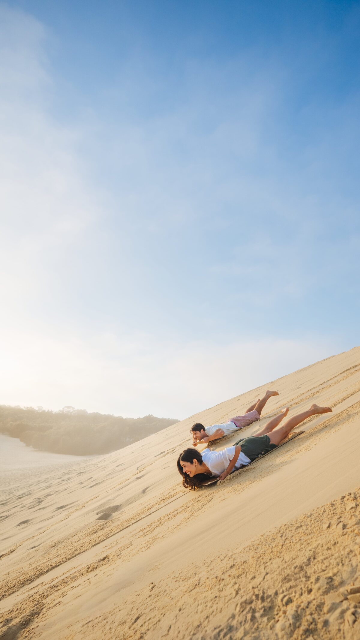 Sandboarding down a Moreton Island dune in the afternoon light.